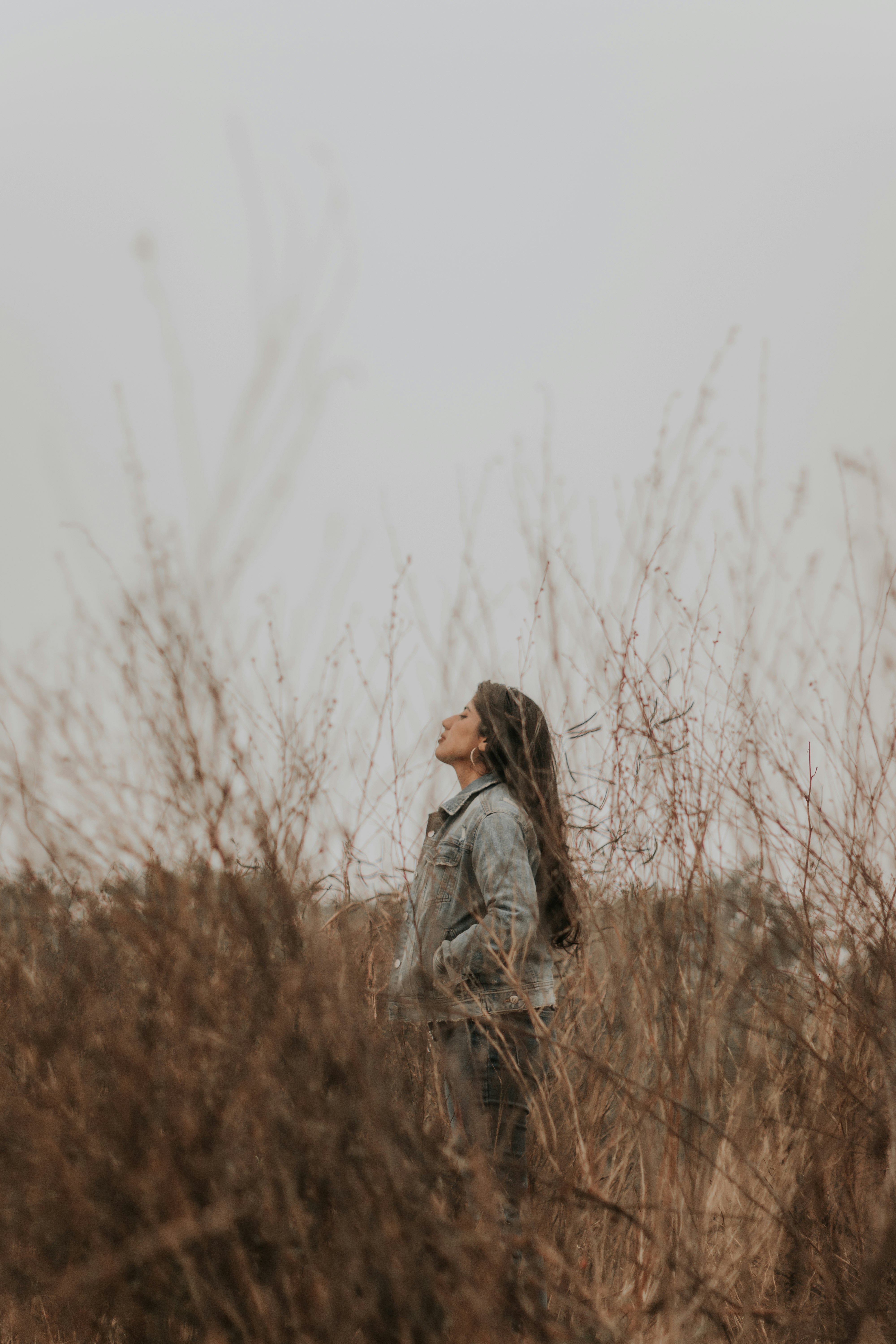 woman in grey jacket standing on brown grass field during daytime